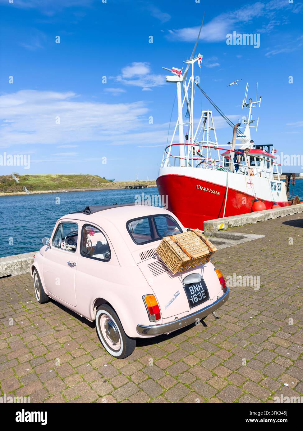 Fiat 500 vintage classique garé sur le quai de Blyth à côté d'un bateau de pêche rouge nommé Charisma - Image de stock capturée avec un smartphone