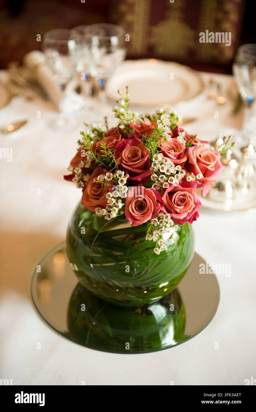 Une rose romantique sur une base de miroir élève une table à manger formelle lors d'une réception de mariage de luxe, créant une scène élégante. Banque D'Images