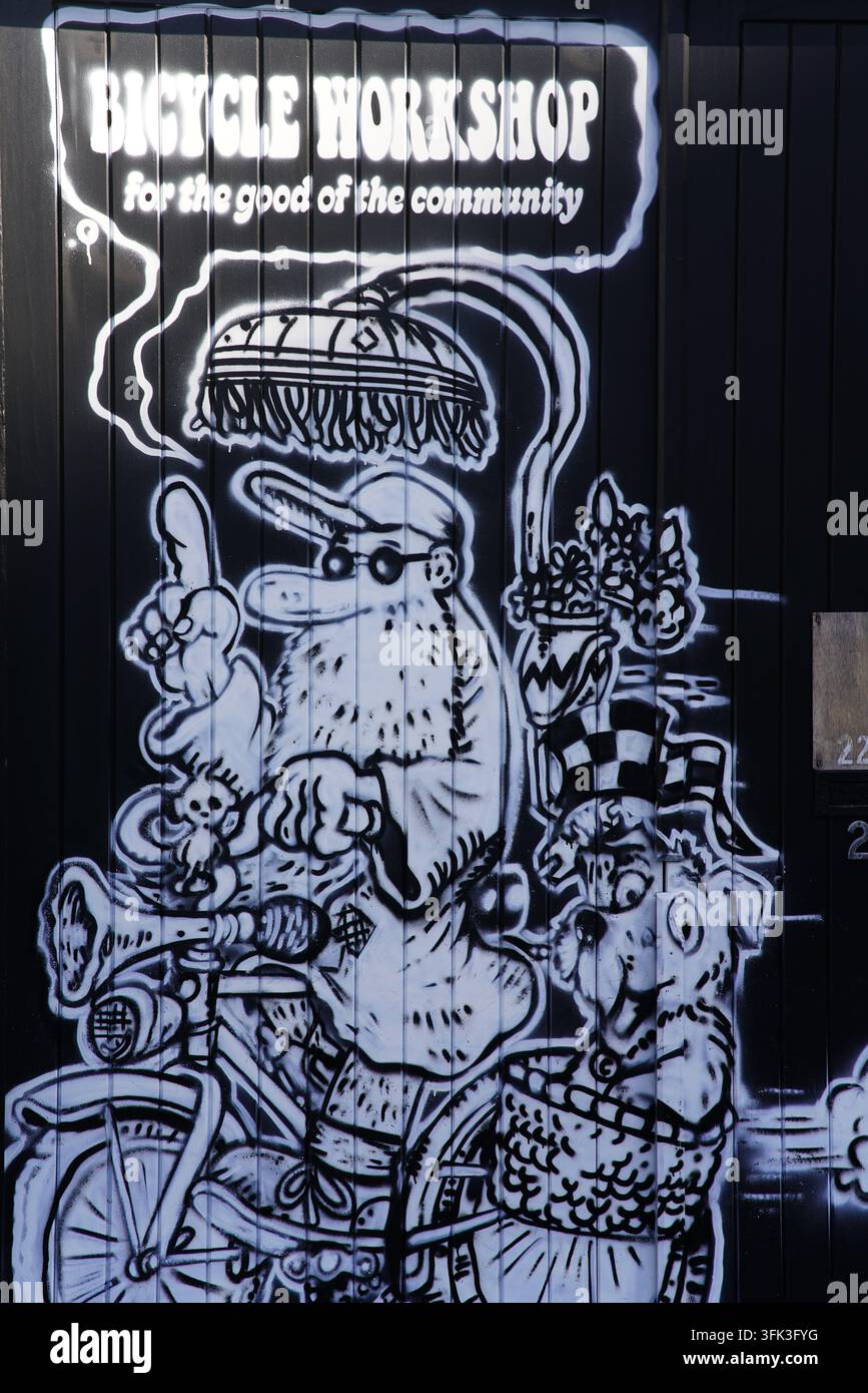 Peinture murale en noir et blanc faisant la promotion d'un atelier de vélos communautaire sur un mur ondulé à Brighton, en Angleterre. Banque D'Images