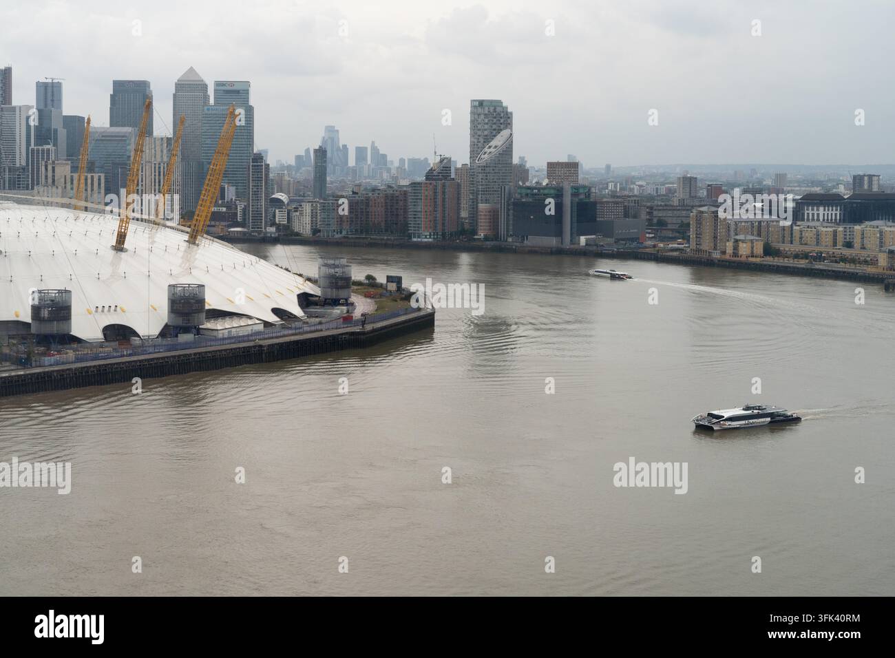 Un ferry Uber Boat navigue sur la Tamise devant l'O2 Arena à Greenwich, Londres, offrant un transport essentiel aux navetteurs. Banque D'Images