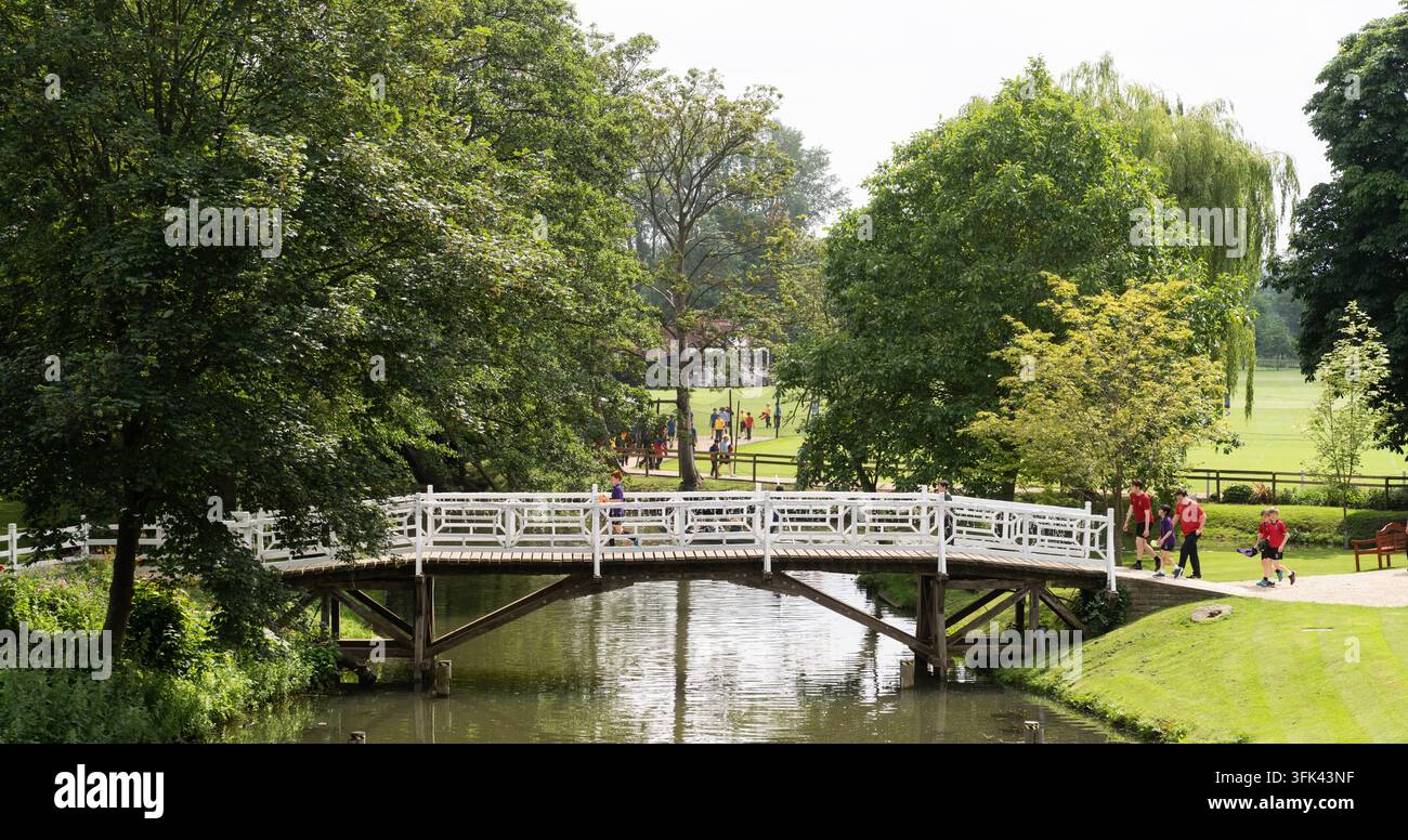 Des étudiants traversent la passerelle au-dessus de la rivière Cherwell à la Magdalen College School d'Oxford, se dirigeant vers l'entraînement sportif. Banque D'Images