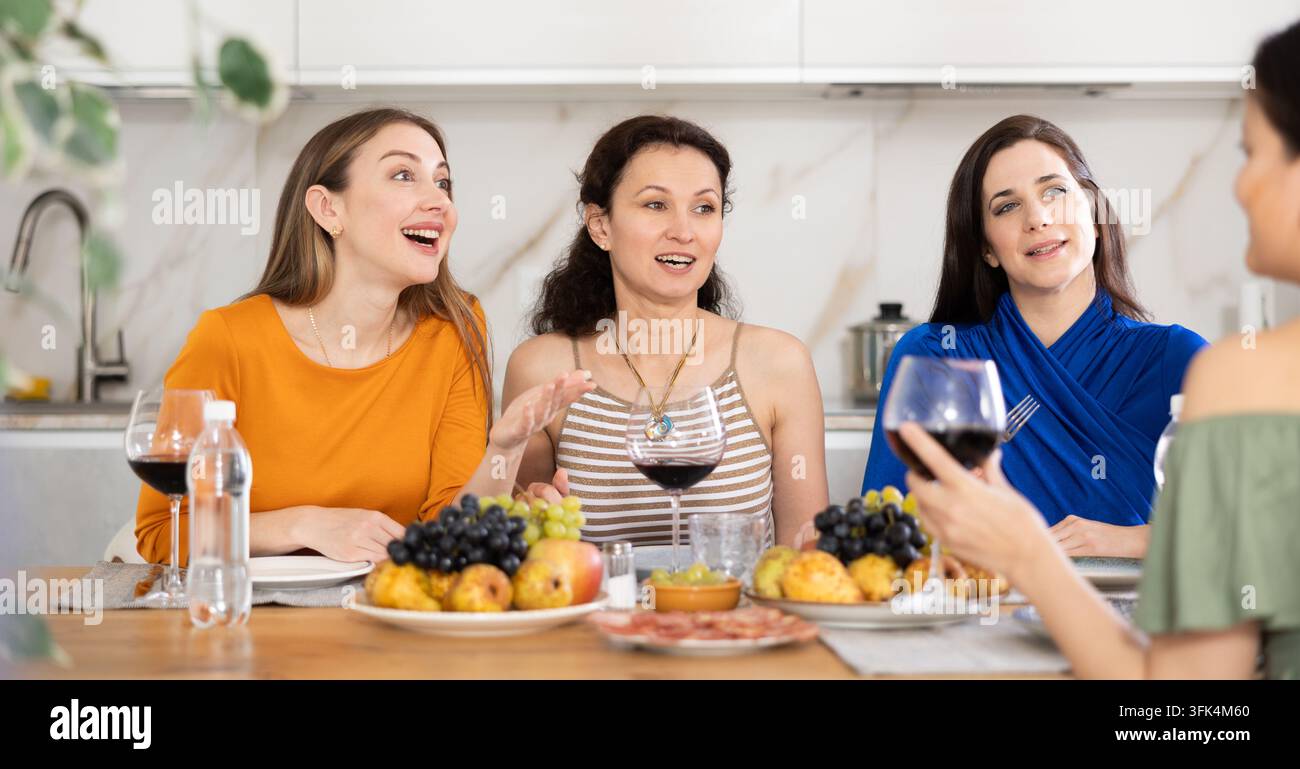 Des femmes heureuses rassemblées autour d'une table festive ; participant à des discussions animées et savourant les délices du vin rouge Banque D'Images