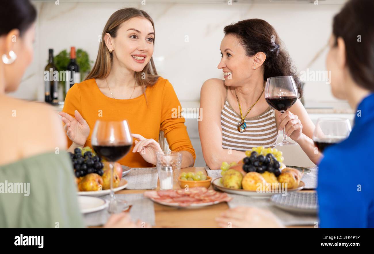 Des femmes heureuses rassemblées autour d'une table festive ; participant à des discussions animées et savourant les délices du vin rouge Banque D'Images