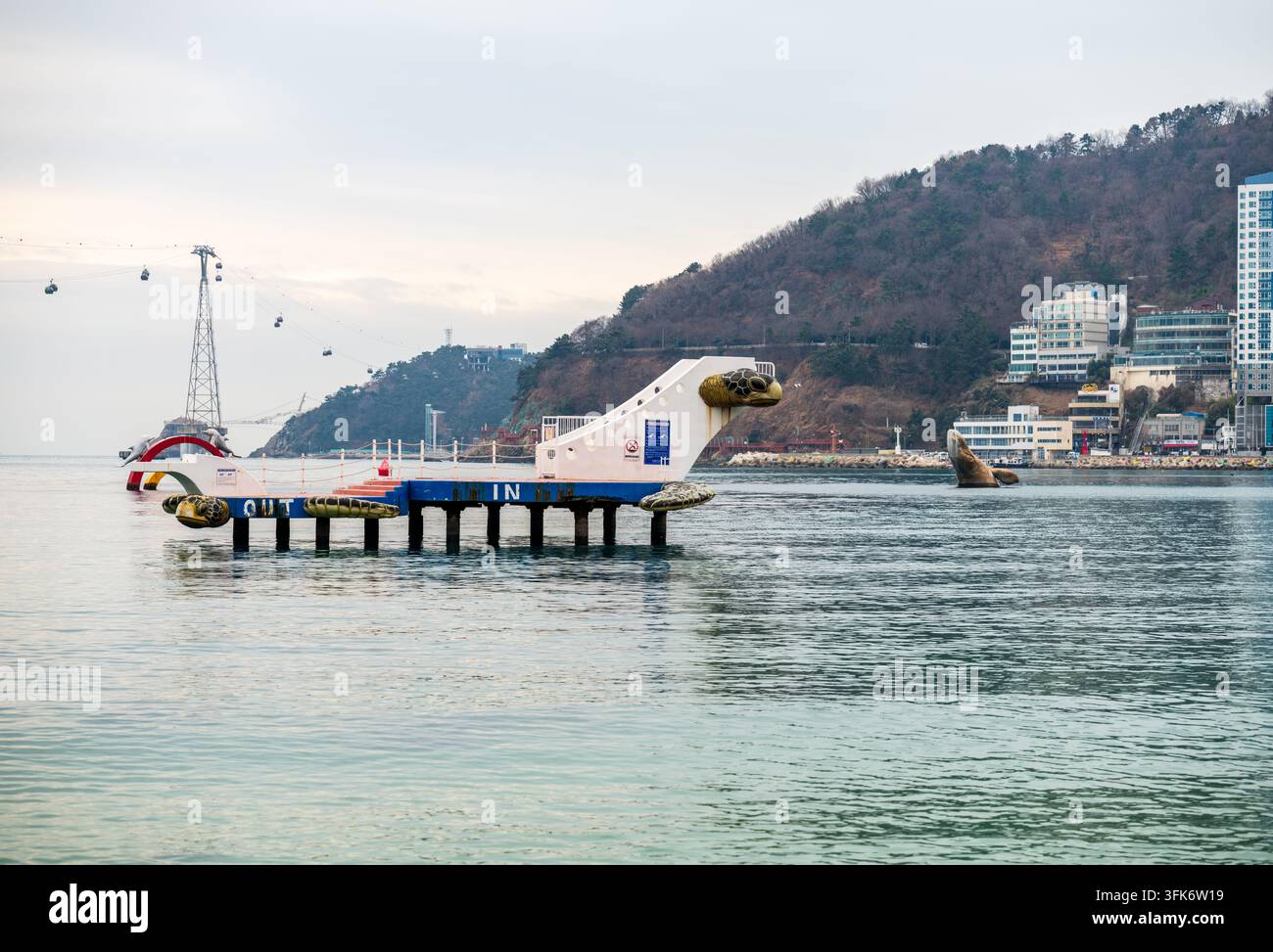 Busan, Corée du Sud - 14 février 2026 : Vue du quai en forme de tortue à la station de Songdo Bay avec le système de téléphérique en arrière-plan. Banque D'Images