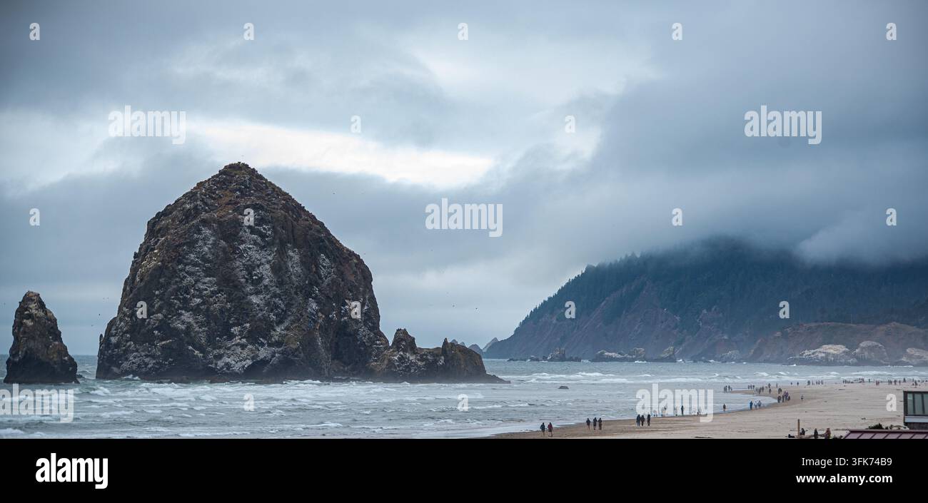 Haystack Rock à Cannon Beach avec une vue grand angle sur les plages environnantes et les montagnes en arrière-plan par une journée nuageuse. Banque D'Images