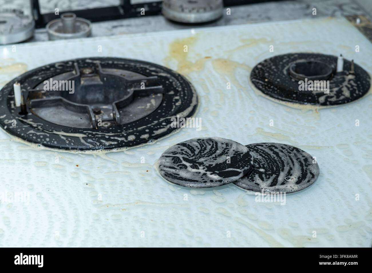 Plaque de cuisson à gaz blanc traité avec de la mousse et un détergent Banque D'Images