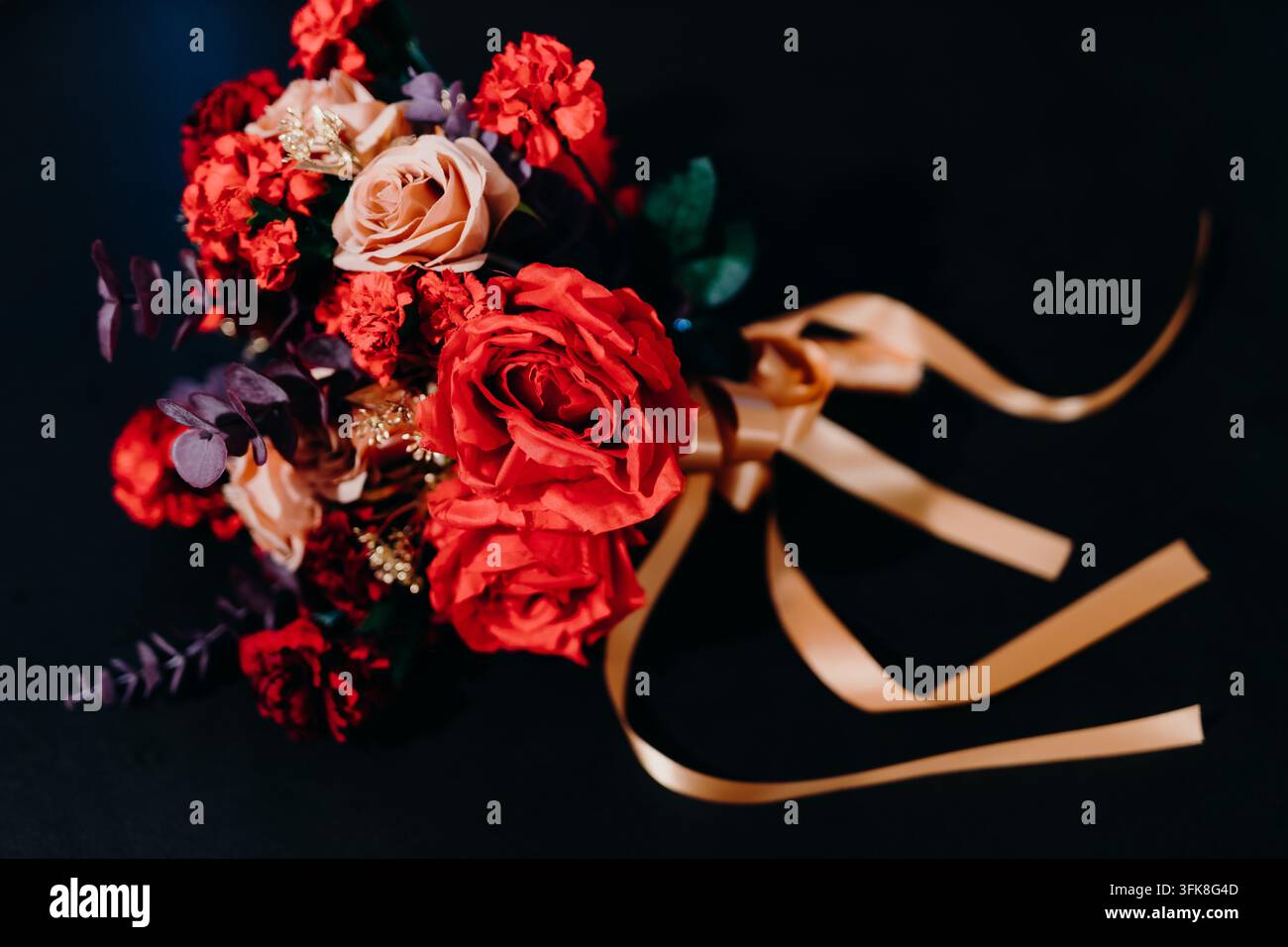 Bouquet de roses rouges de luxe avec ruban en satin doré sur fond sombre Banque D'Images