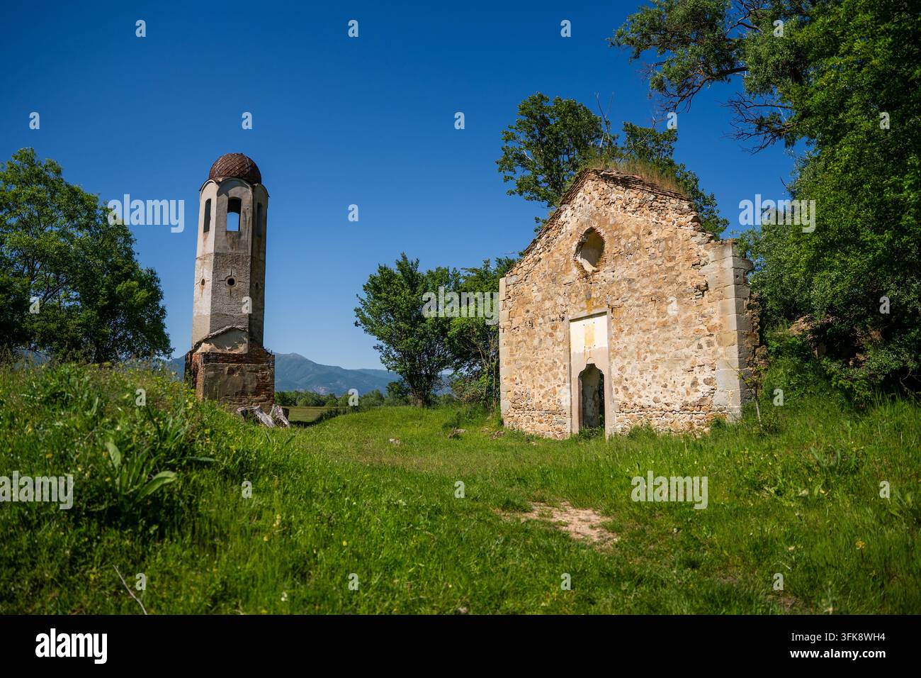 Vue des ruines de l'église du monastère Saint-Georges avec son clocher détaché se dressant dans une prairie verdoyante à Viden, Stara Zagora, Bulgarie. Banque D'Images