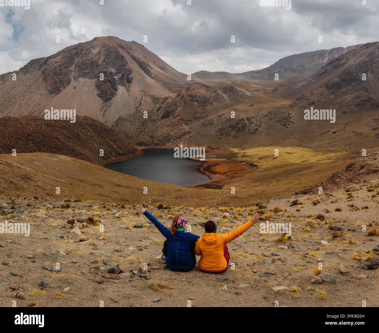 Deux voyageurs assis ensemble profitant d'une vue panoramique sur un lac de montagne dans les Andes boliviennes Banque D'Images