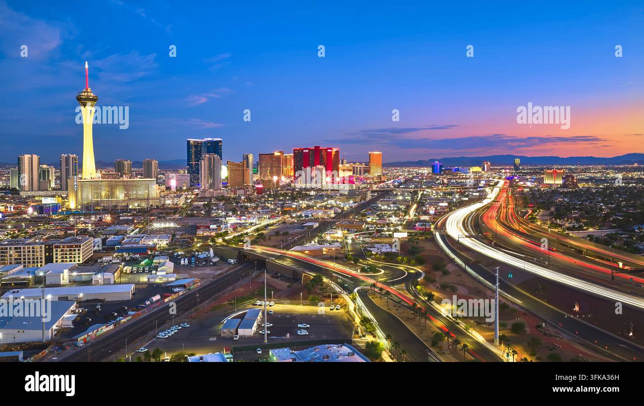 Vue aérienne du Strip de Las Vegas dans le Nevada à l'heure bleue avec des lumières de ville vibrantes et des traînées de voitures lumineuses. La tour Stratosphere et le ciel urbain coloré Banque D'Images