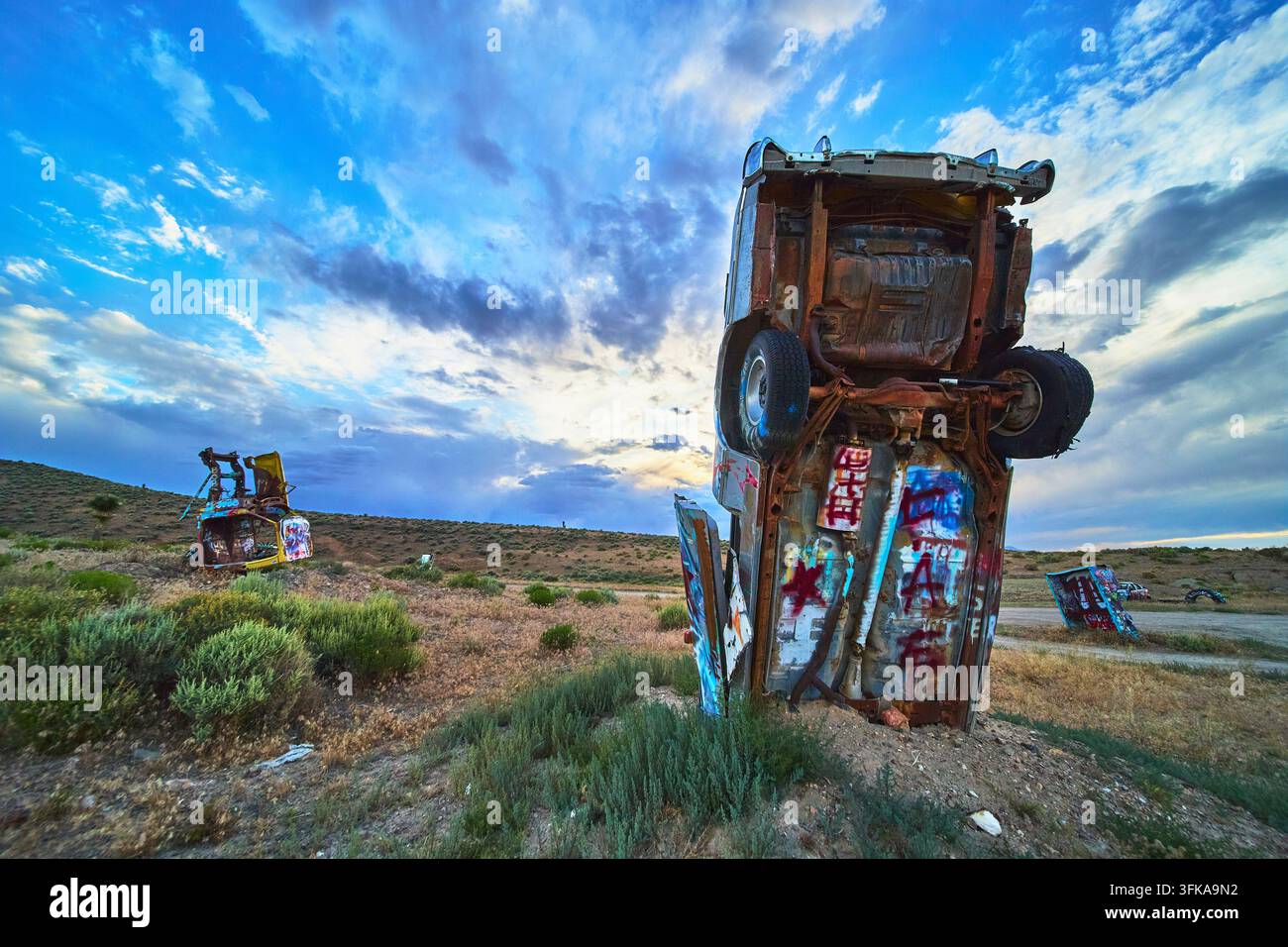 Des véhicules abandonnés couverts de graffitis se dressent droit dans le désert du Nevada à la Forêt Internationale de Voitures près de Goldfield. L'art de rue vibrant contraste Banque D'Images