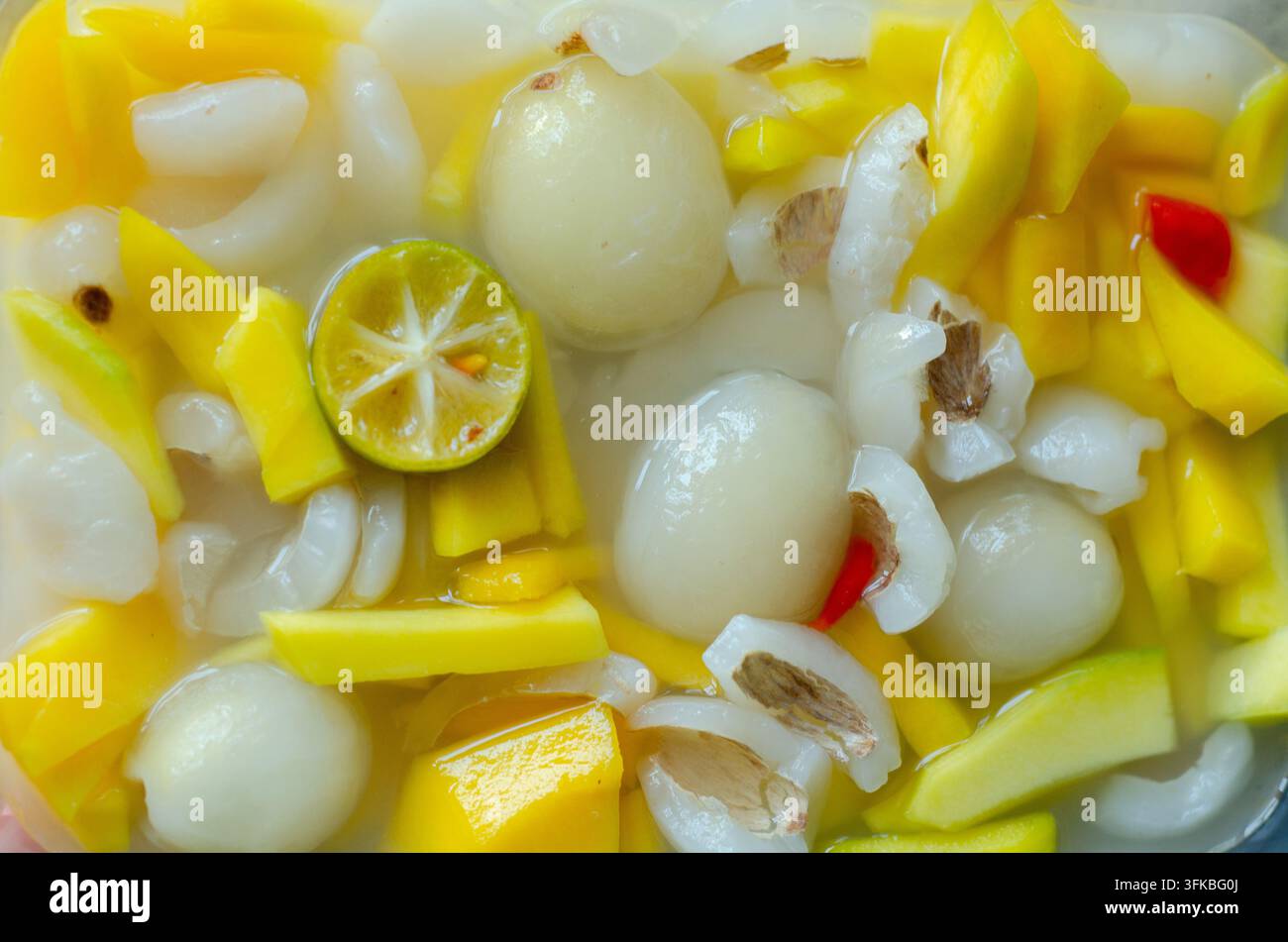 Mélange rafraîchissant de tranches de mangue mûres, de litchis entiers et de quartiers de citron vert dans un sirop léger, une parfaite rafraîchissement tropical Banque D'Images