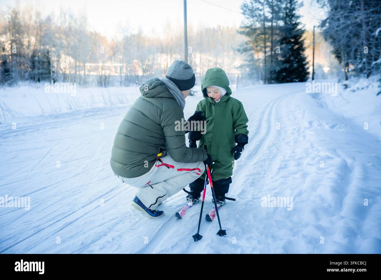 Un père aide son tout-petit à apprendre le ski de fond sur un sentier enneigé dans la région d'Helsinki, en Finlande, lors d'une sortie familiale active en hiver. Banque D'Images