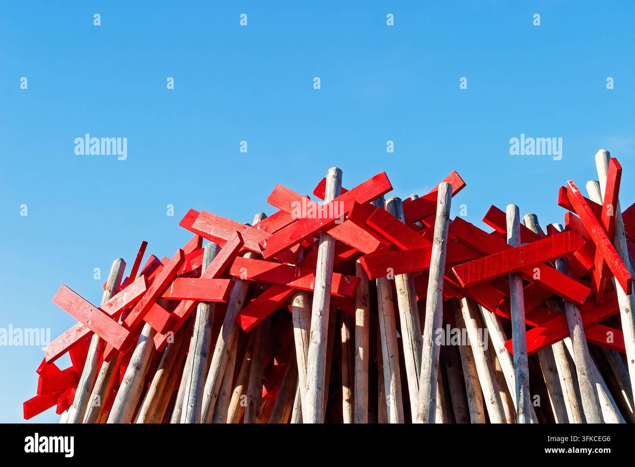 Collection de marqueurs de sentier en bois rouge en forme de croix empilés sous un ciel bleu clair Banque D'Images
