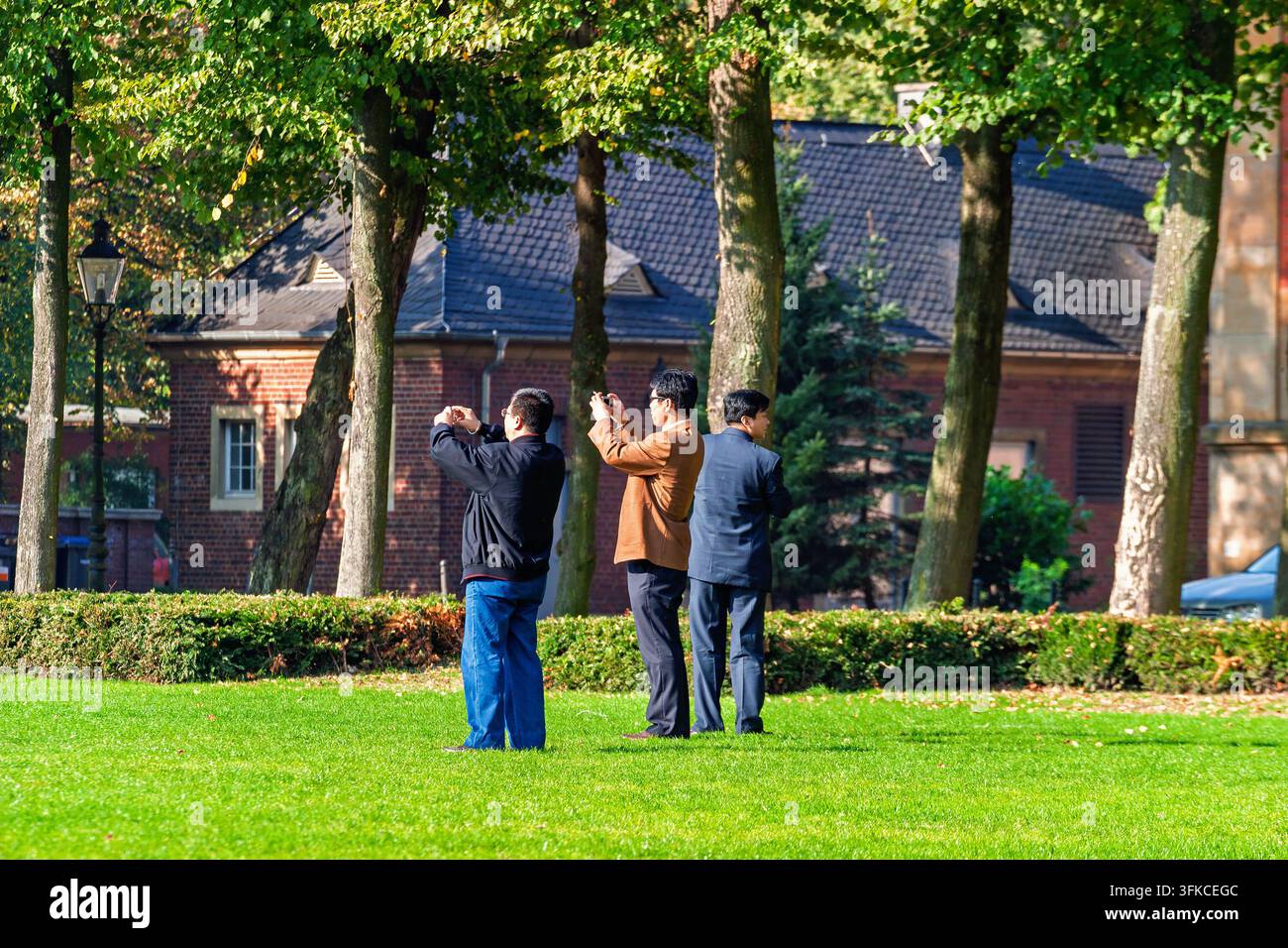 Visiteurs asiatiques photographiant une architecture historique dans un cadre de parc en Allemagne Banque D'Images