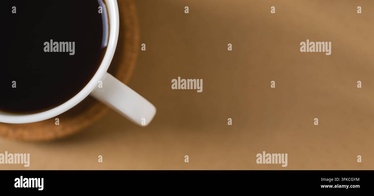Vue de dessus d'une tasse de café noire sur un fond brun minimaliste chaud Banque D'Images