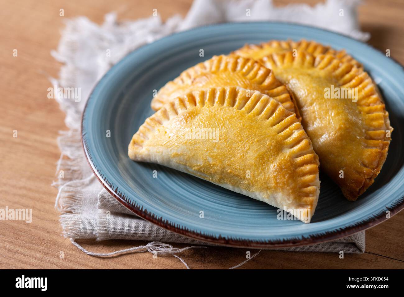 Assiette remplie d'empanada maison dorée sur une table en bois Banque D'Images