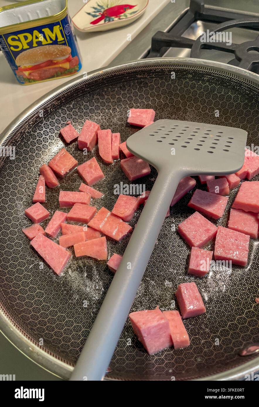 Viande en conserve Spam coupée en dés cuisant dans une poêle sur une cuisinière domestique, États-Unis, 2026 Banque D'Images