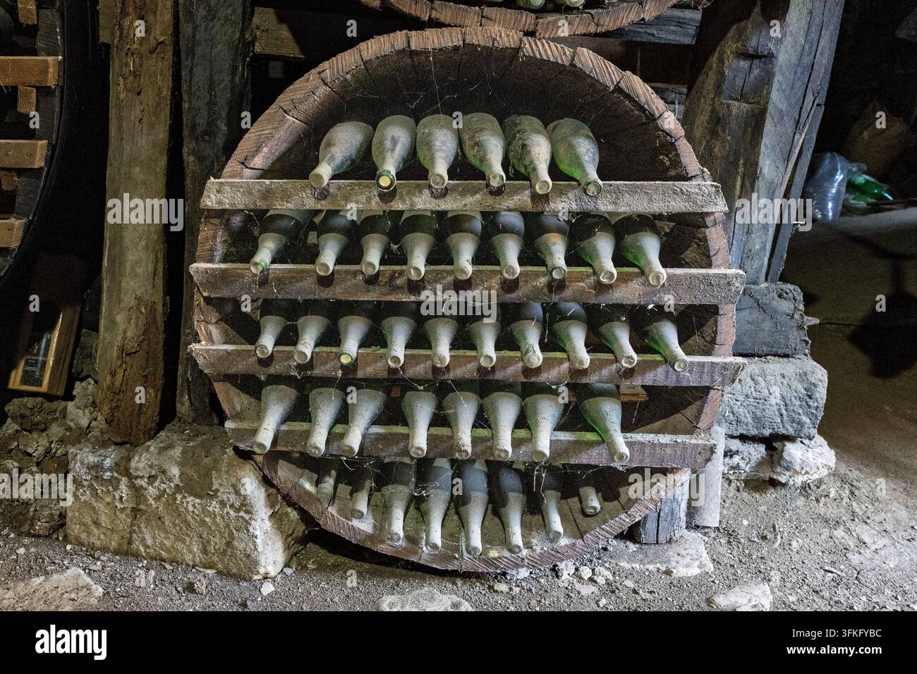 Bouteilles de vin poussiéreuses vieillissant sur des étagères en bois façonnées en forme de tonneau  Maison de vin Radosavijevic, village de Rogijevo, Serbie Banque D'Images