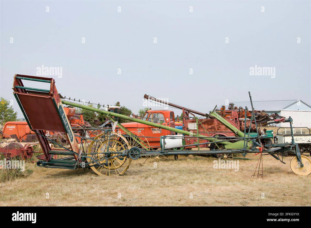 IRRICANA, ROCKY VIEW COUNTY, ALBERTA, CANADA – 08 AOÛT 2026 : Une collection extérieure de machines agricoles anciennes debout sur de l'herbe sèche sous un p Banque D'Images