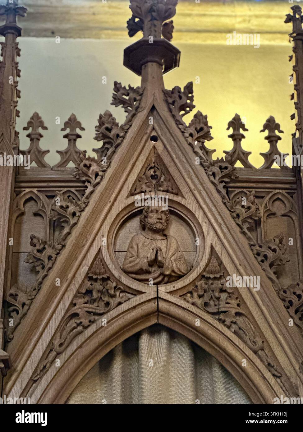Sculpture sur bois complexe d'une figure en prière dans l'intérieur d'une église gothique. Sculpture sur bois gothique détaillée représentant un saint ou une figure en prière dans un cercle Banque D'Images