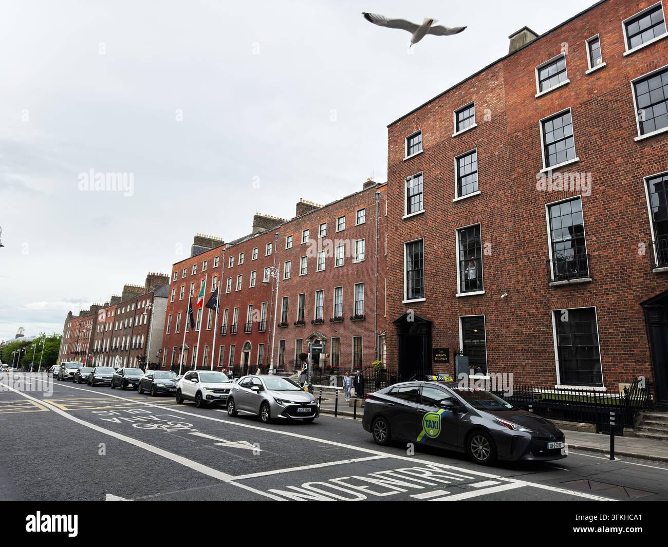 Dublin, Irlande – 22 mai 2026 : Taxi et voitures garées le long des maisons de ville Merrion en brique géorgienne sur une rue de Dublin sous un ciel couvert. Banque D'Images