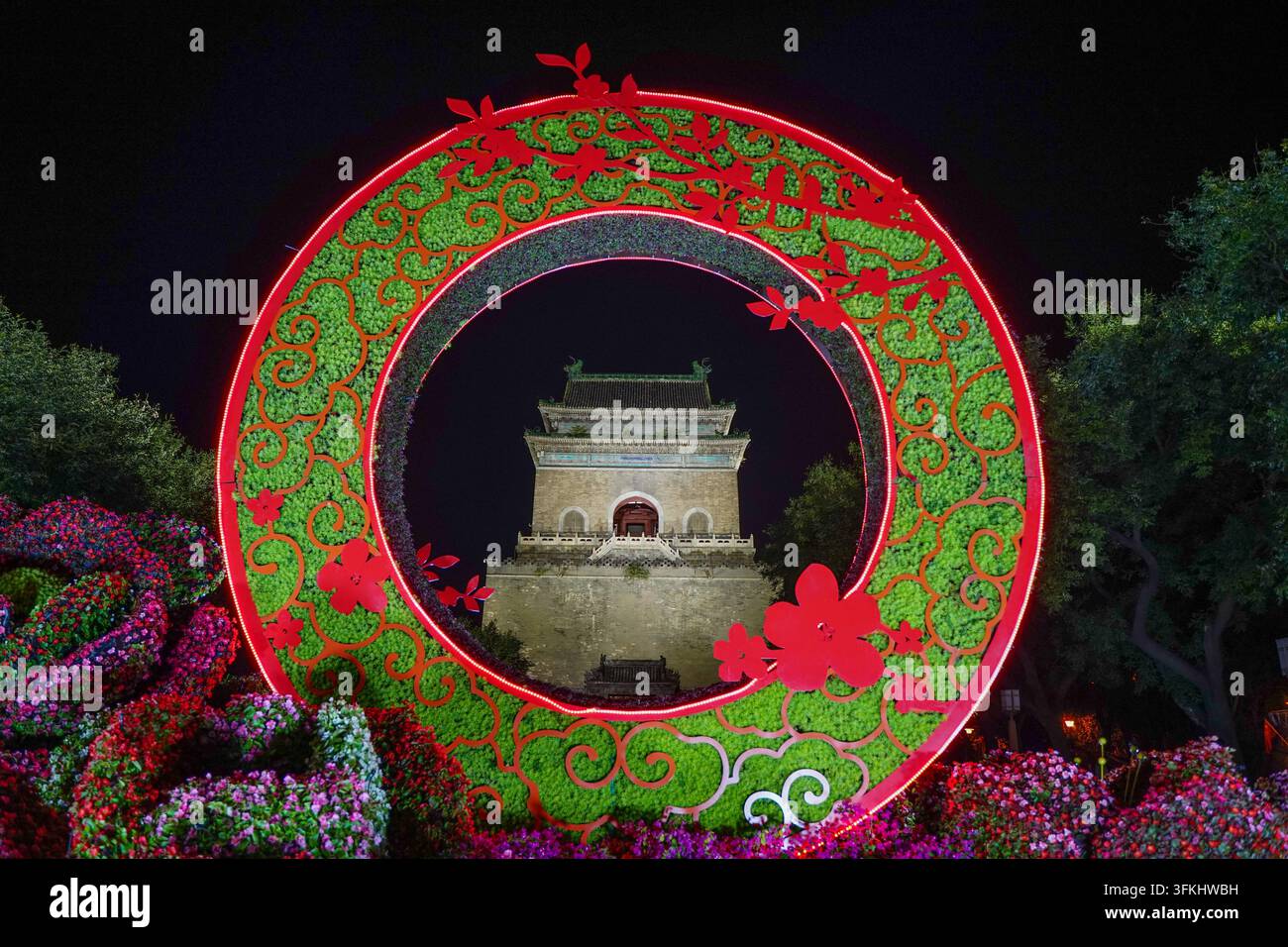 Vue encadrée de la Tour de la Cloche de Pékin la nuit à travers un parterre circulaire Banque D'Images