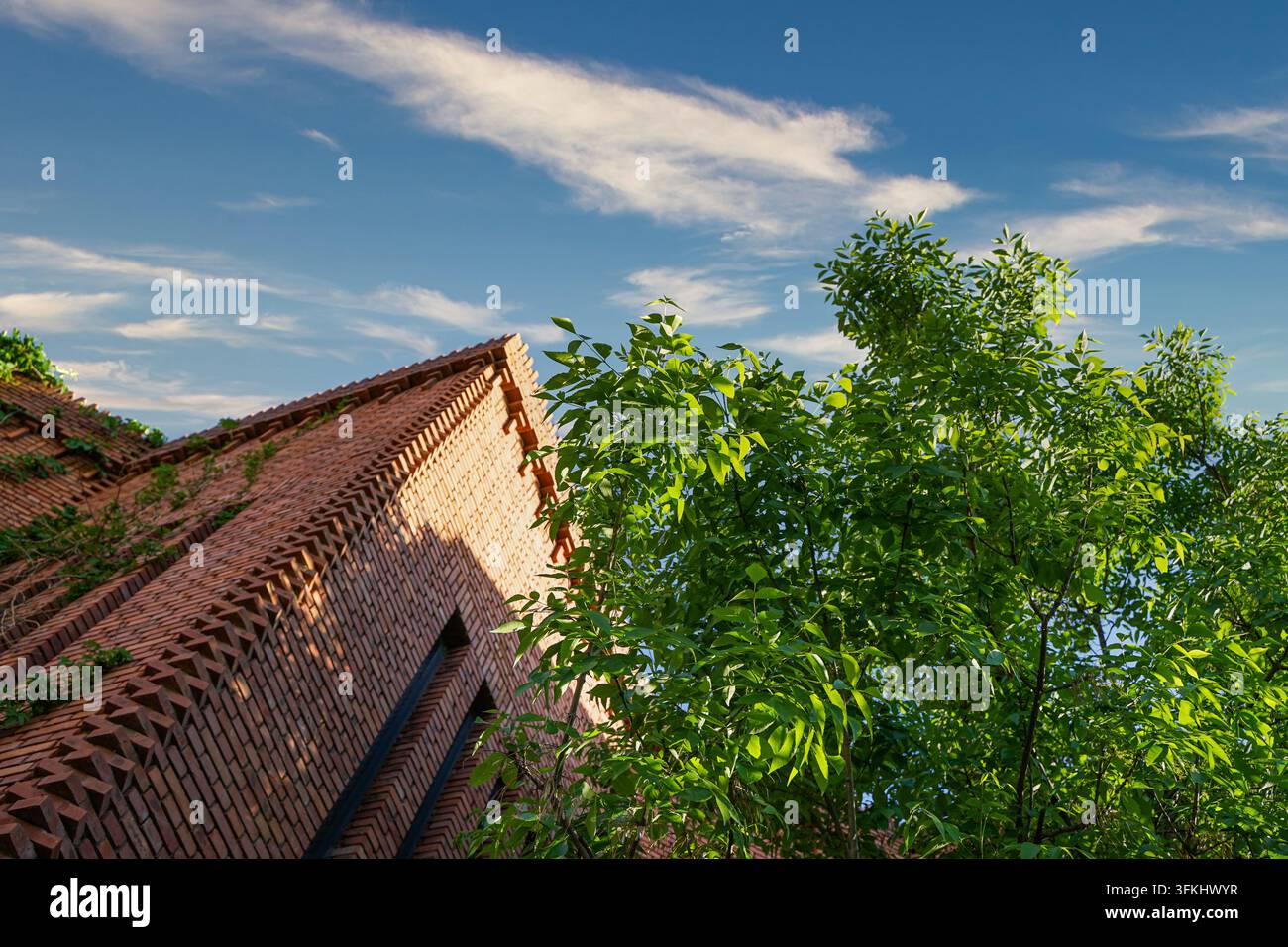Prise de vue en contre-plongée de la façade en pente du musée d'art en briques rouges avec des arbres verts Banque D'Images