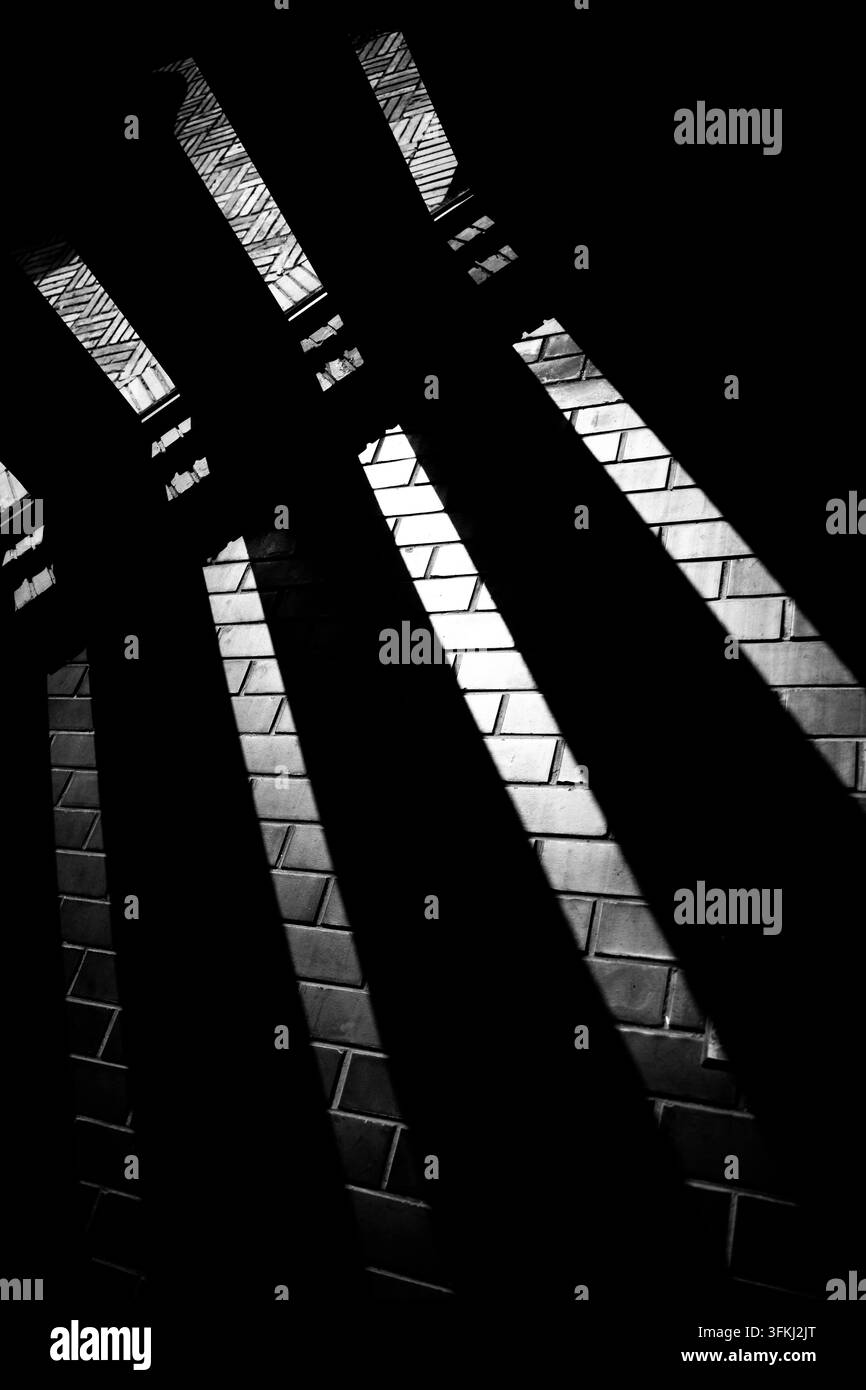 Photo noir et blanc d'ombres diagonales sur un mur de briques rouges à travers les vitres Banque D'Images
