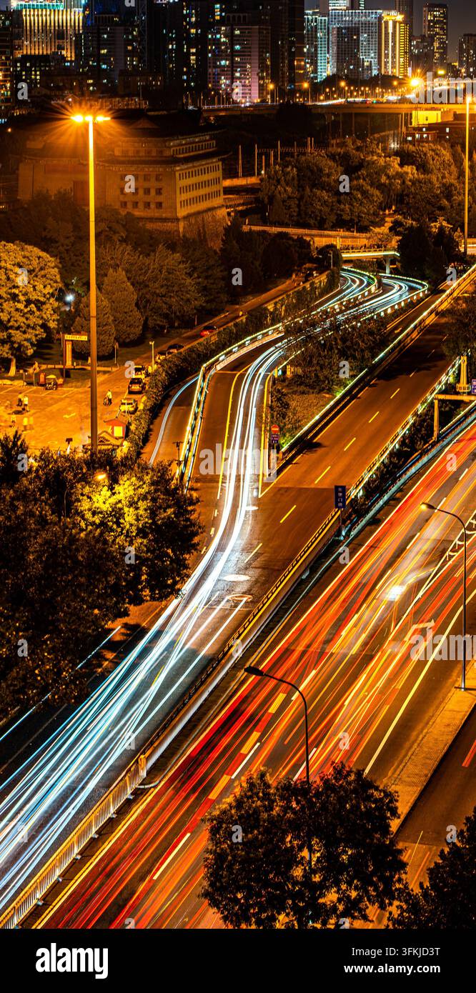 Pont d'autoroute urbaine de Pékin la nuit avec traînées de lumière des véhicules et bannières verticales Banque D'Images