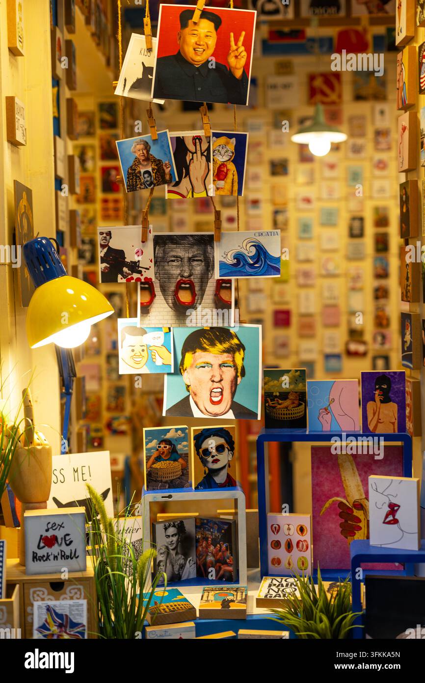 Cartes postales et impressions d'art colorées dans une boutique de souvenirs. Des cartes postales et impressions d'art colorées sont accrochées dans une boutique de souvenirs chaleureusement éclairée, remplie de portraits Banque D'Images