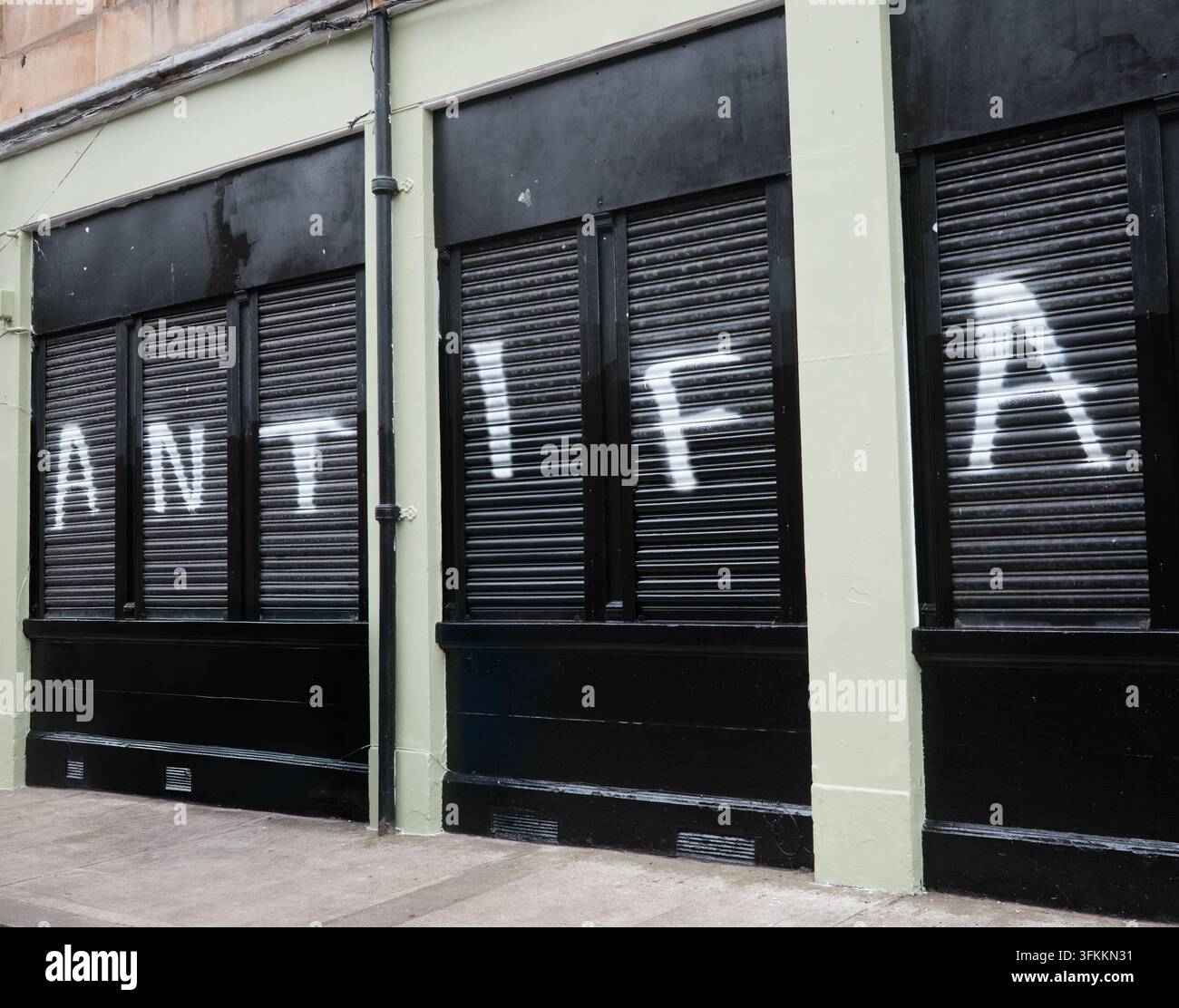 Texte Antifa peint en blanc sur des volets de sécurité noirs Banque D'Images