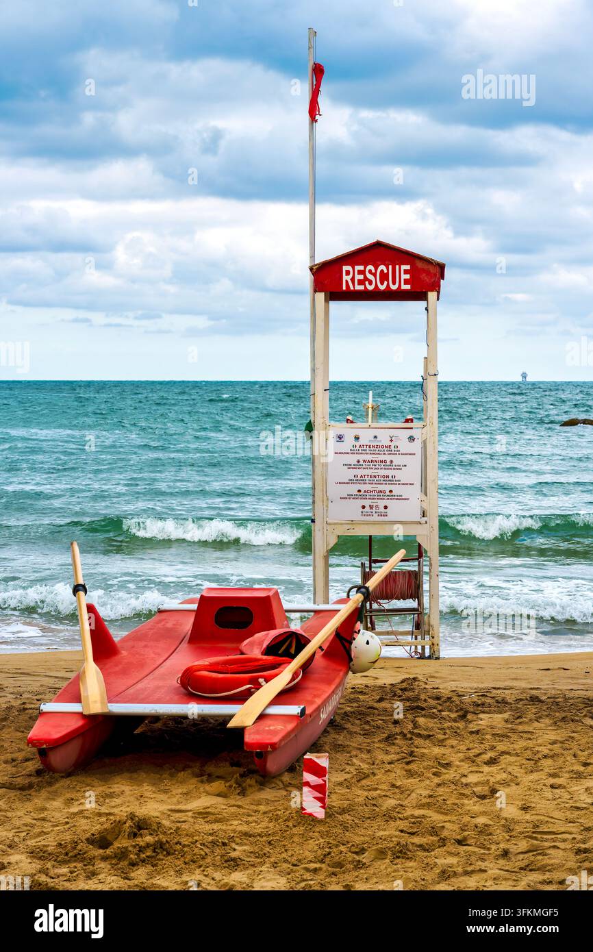 Bateau de secours rouge et tour de sauvetage avec drapeau rouge sur la plage de Pescara, Italie Banque D'Images