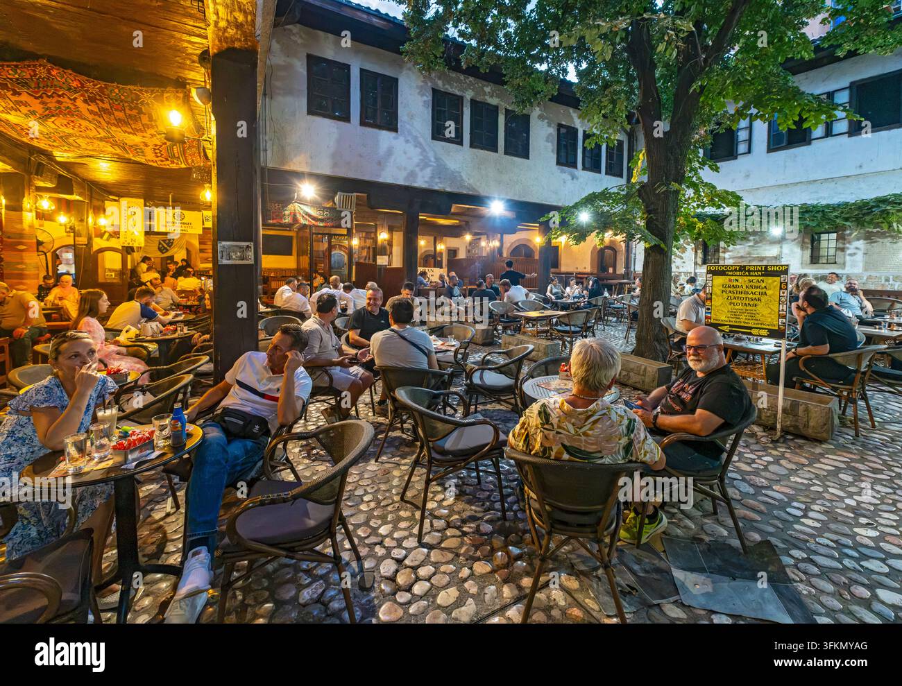 Des gens se détendent à des tables en terrasse dans la cour intérieure atmosphérique du Morića Han historique à Sarajevo, Bosnie-Herzégovine Banque D'Images