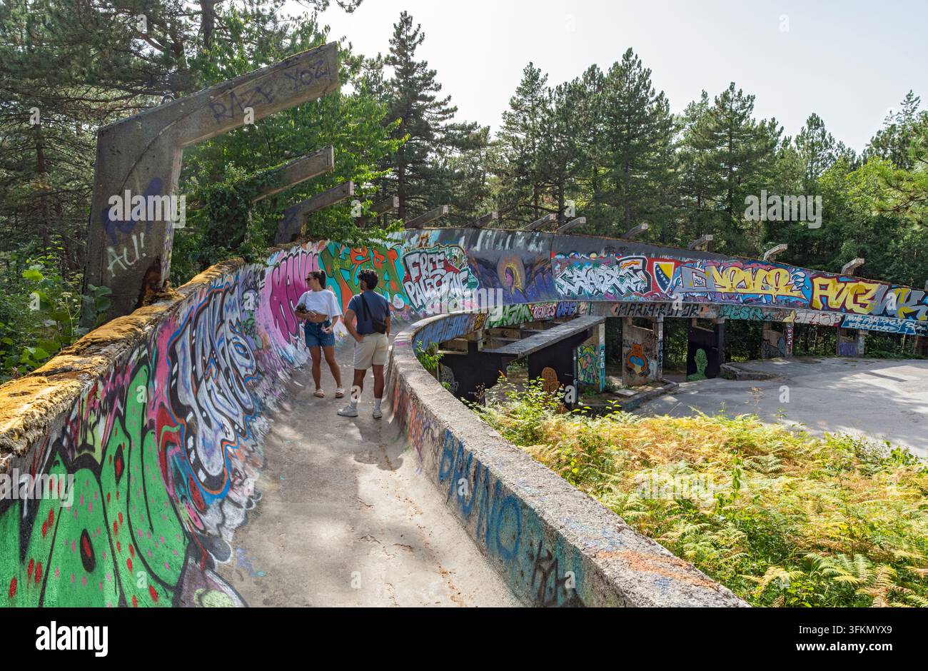 Visiteurs marchant le long de la piste de bobsleigh abandonnée de 1984 couverte de graffitis sur le mont Trebević, à Sarajevo, Bosnie-Herzégovine Banque D'Images