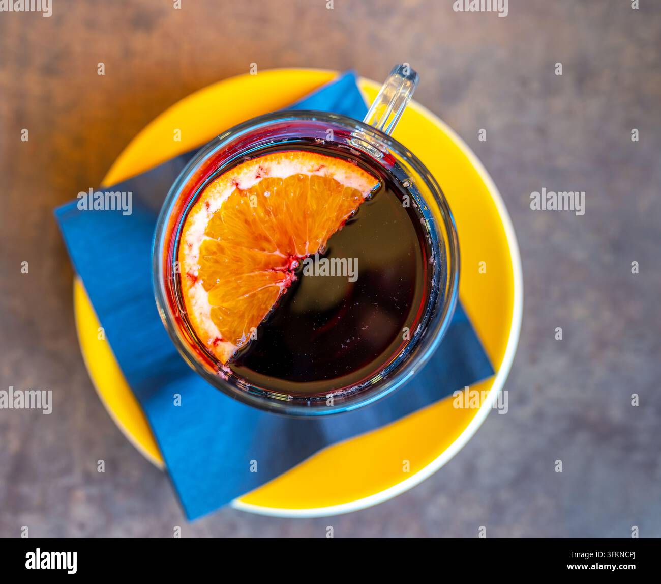 Vue de dessus d'une tasse de vin chaud avec une demi-orange flottant à la surface, posée sur une table en bois rustique pendant l'hiver. Banque D'Images