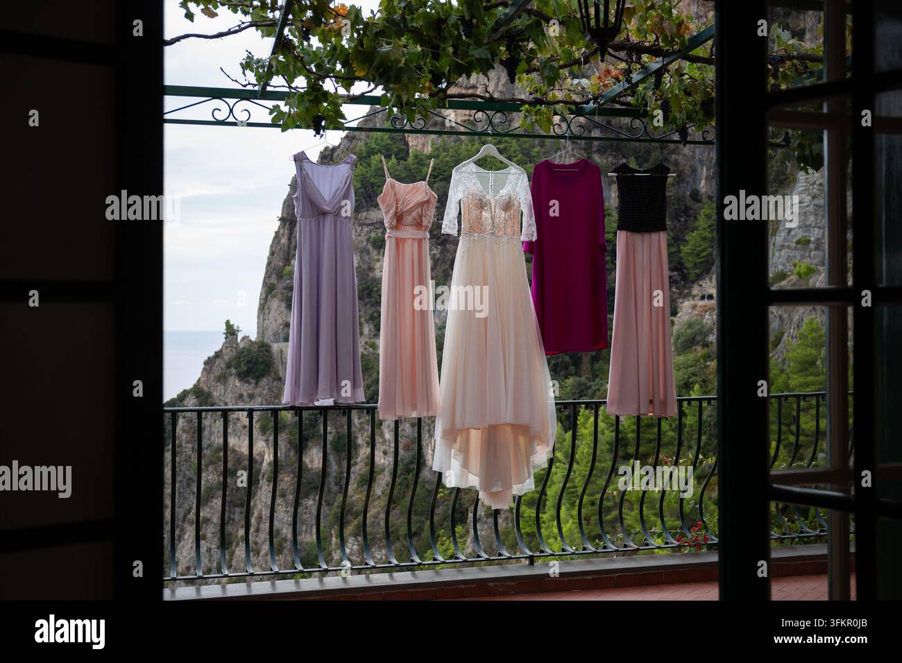 Robes de mariage et de demoiselles d'honneur suspendues sur une terrasse avec fond de falaise à Positano, Italie. Banque D'Images
