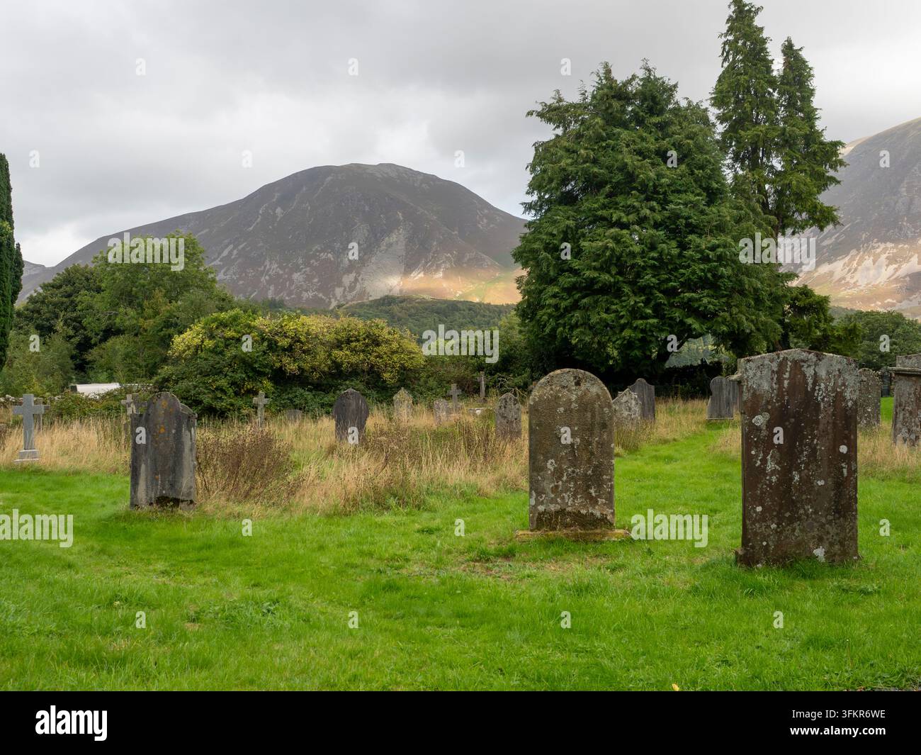 20 septembre 2026, Loweswater, Royaume-Uni. Une vue atmosphérique d’un vieux cimetière avec des pierres tombales érodées se détachant sur un fond de collines ondulantes Banque D'Images
