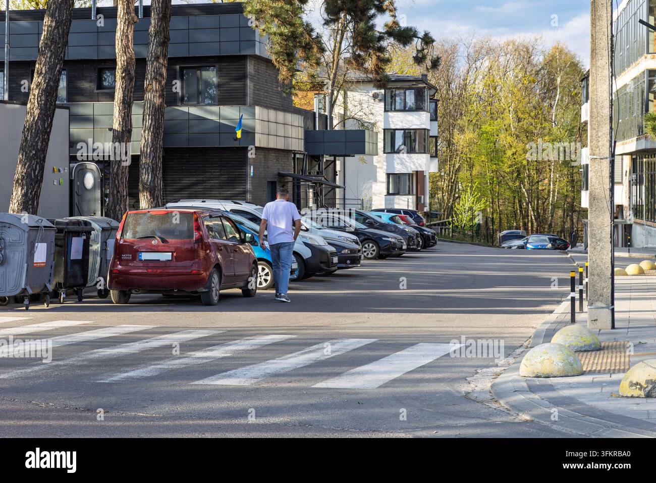Homme marchant dans une zone de stationnement près de bâtiments modernes à Lviv, en Ukraine Banque D'Images