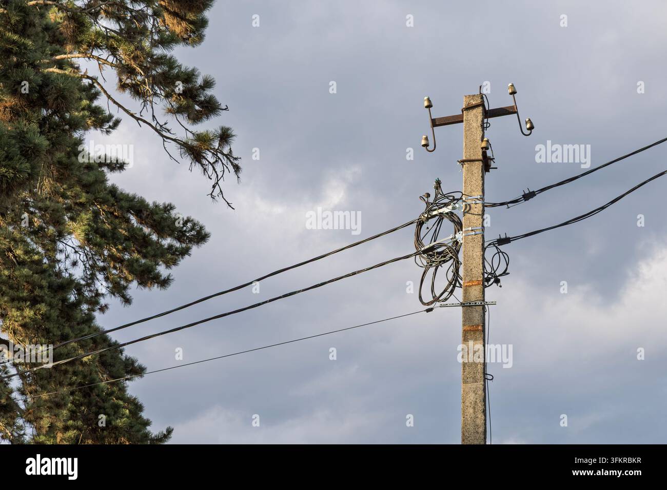 Poteau utilitaire avec câbles électriques et de communication contre un ciel nuageux Banque D'Images