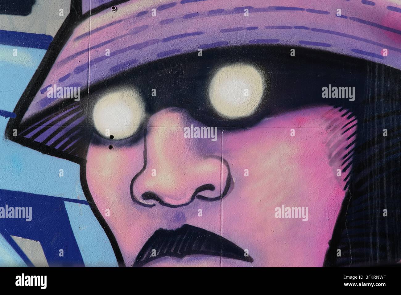 Close-up d'une fresque murale REQ montrant une figure portant un chapeau seau violet avec des yeux lumineux à Brighton, en Angleterre Banque D'Images