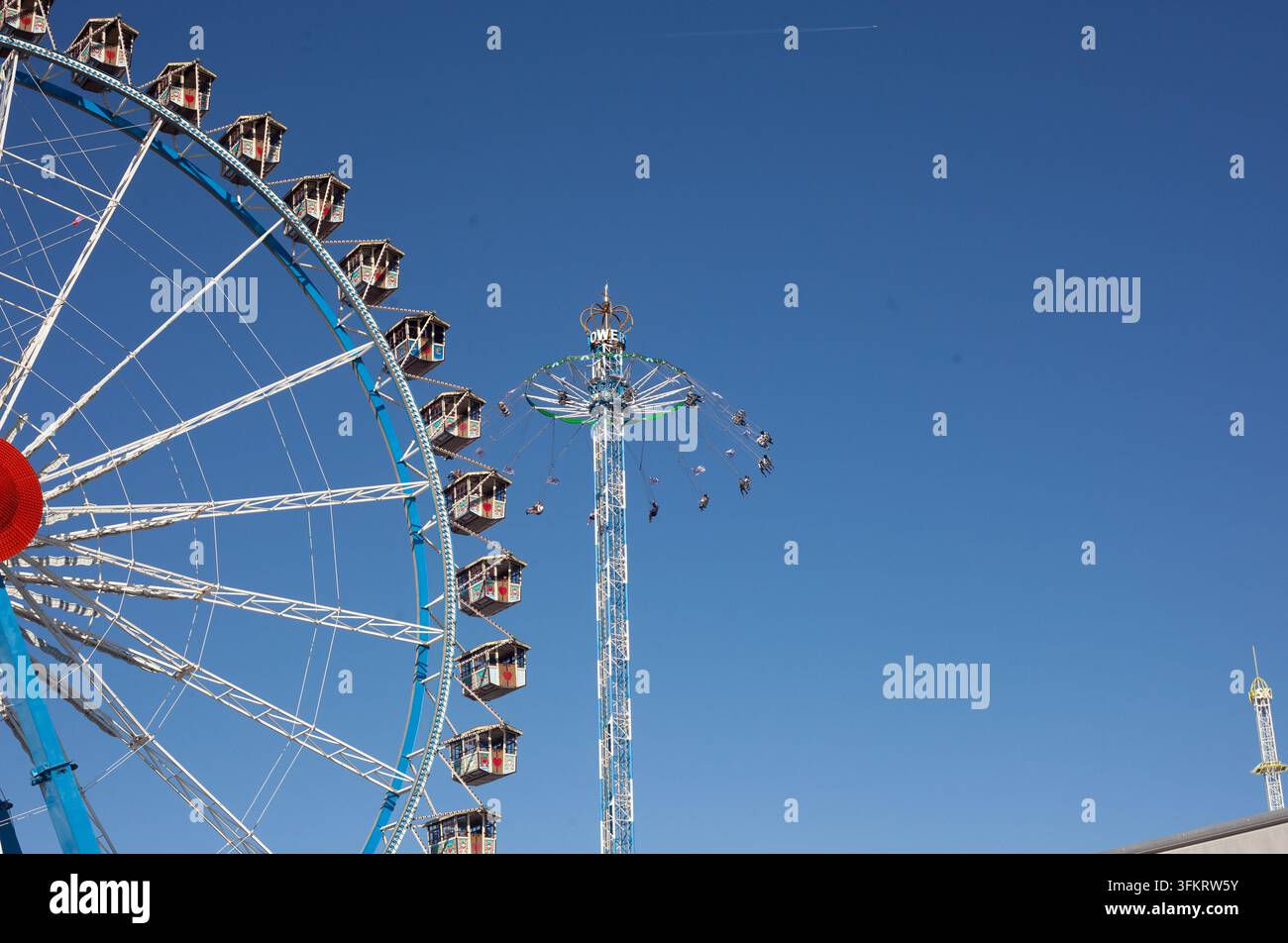 Une grande roue et une balançoire sur fond de ciel bleu clair lors du festival traditionnel de la Wiesn de Munich, l'Oktoberfest en Bavière, Allemagne. Banque D'Images