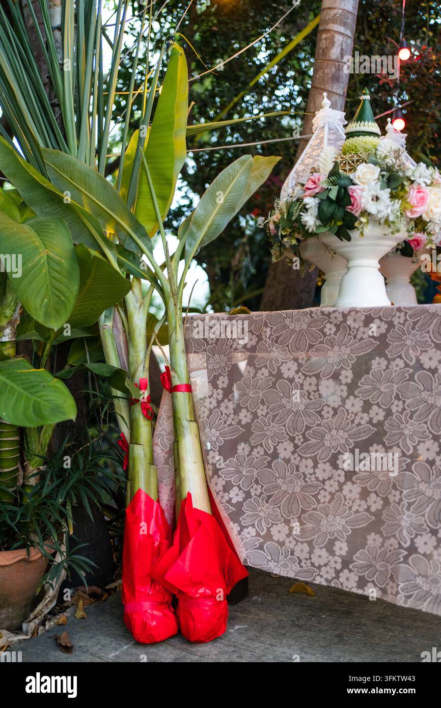 Rejets de bananier enveloppés dans du papier rouge à côté d'une table de réception de mariage Banque D'Images