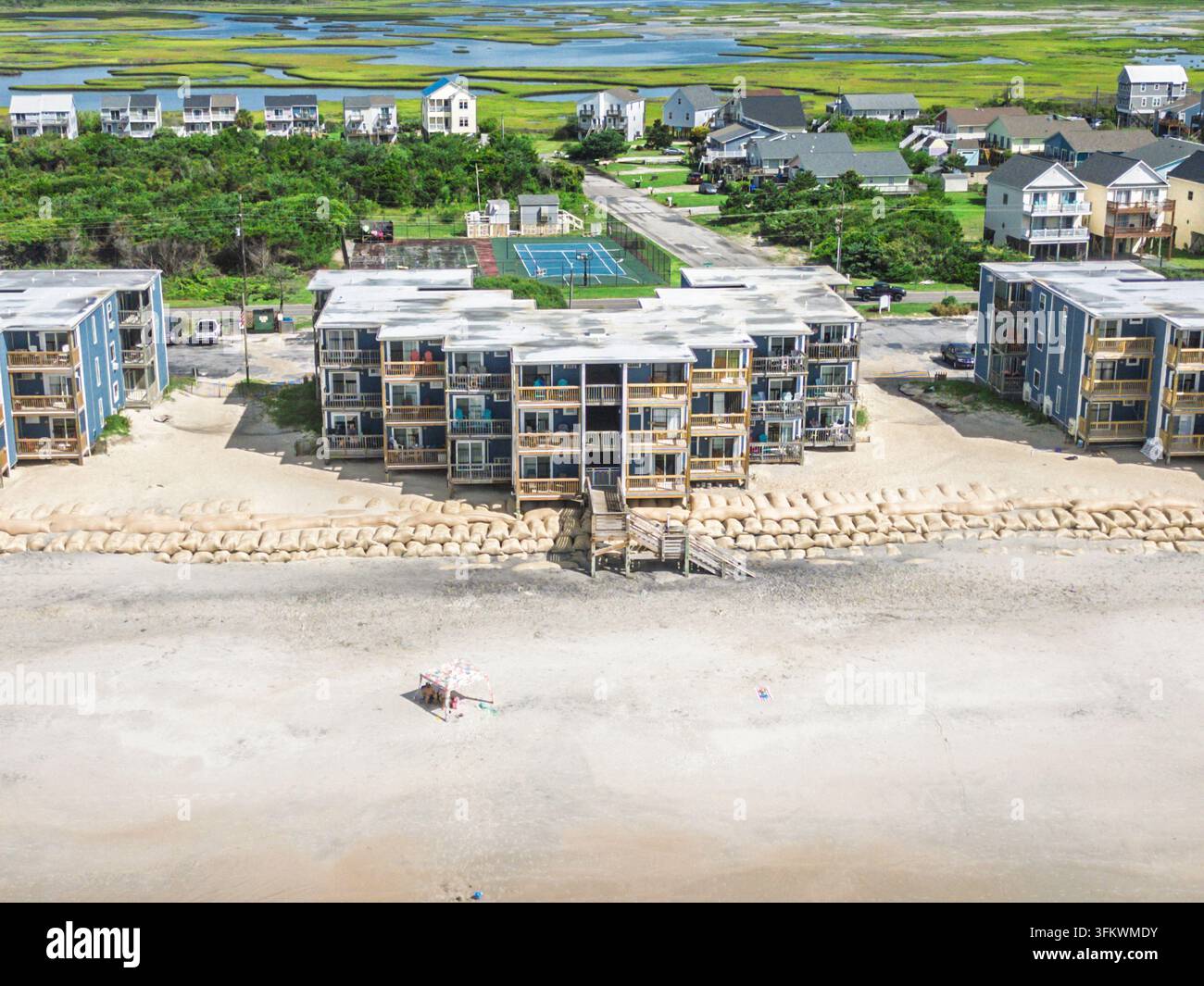 Vue aérienne de condominiums en bord de plage avec balcons en bois, sacs de sable le long des dunes et une petite tente sur la plage de sable à North Topsail Beach, No Banque D'Images