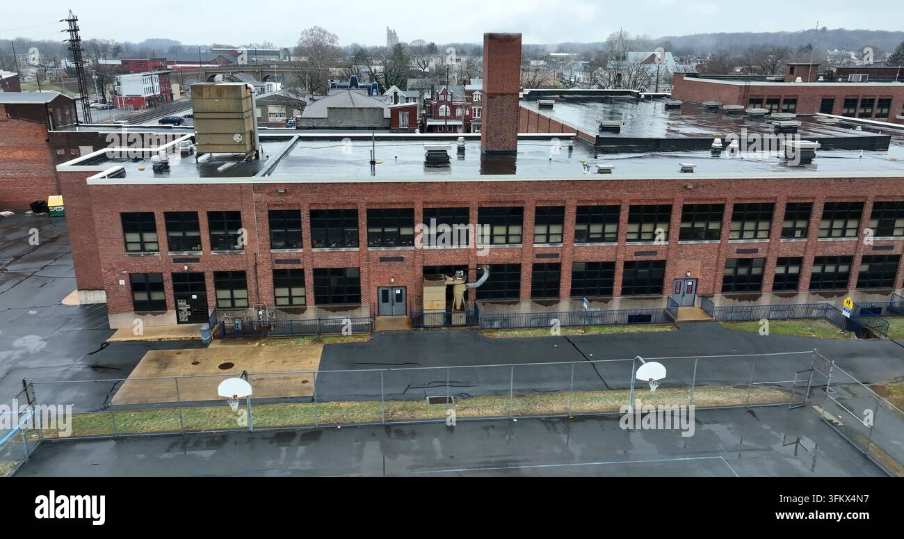 Vue aérienne d'un bâtiment scolaire en briques avec un toit plat et un terrain de basket-ball au premier plan à Fort Indiantown Gap, Pennsylvanie, États-Unis. Banque D'Images