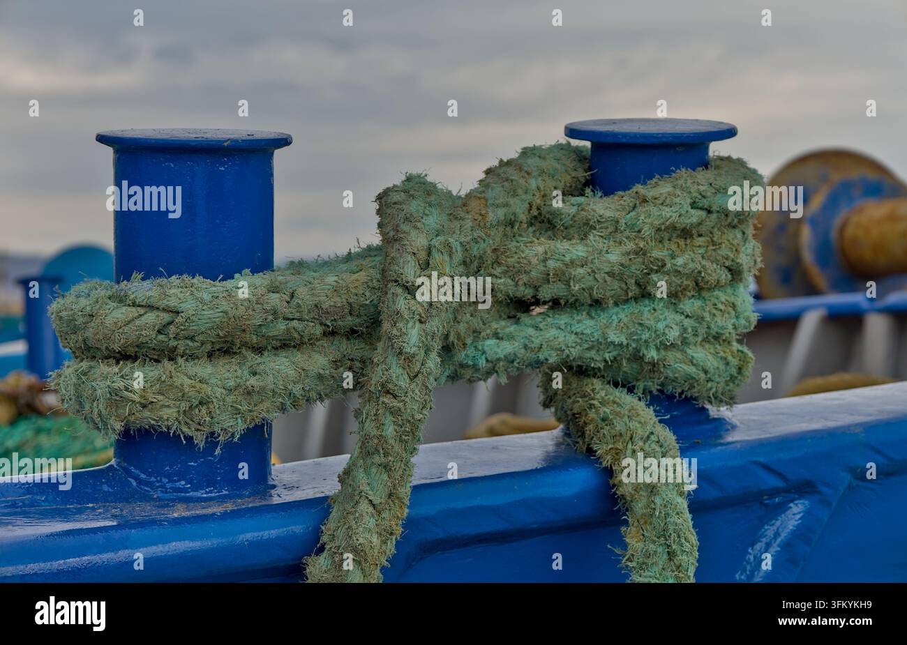 Close-up d'une corde d'amarrage verte enroulée autour de bollards peints en bleu à bord d'un navire dans le port de Rafina, Attique orientale, Grèce Banque D'Images