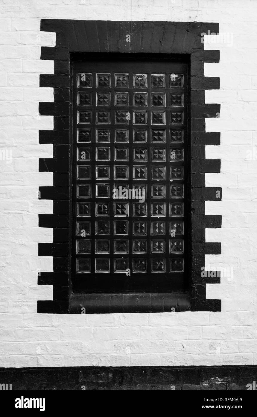 Fenêtre en blocs de verre noir et blanc dans un encadrement de briques à motifs sur une façade de Glasgow Banque D'Images