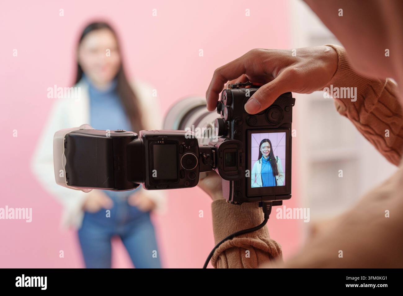 Gros plan depuis la perspective du photographe montrant l'image de la caméra avec un portrait d'une modèle féminine souriante en studio Banque D'Images