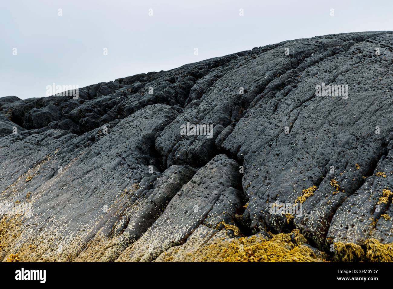 Texture de roche basaltique volcanique sombre avec fissures Banque D'Images
