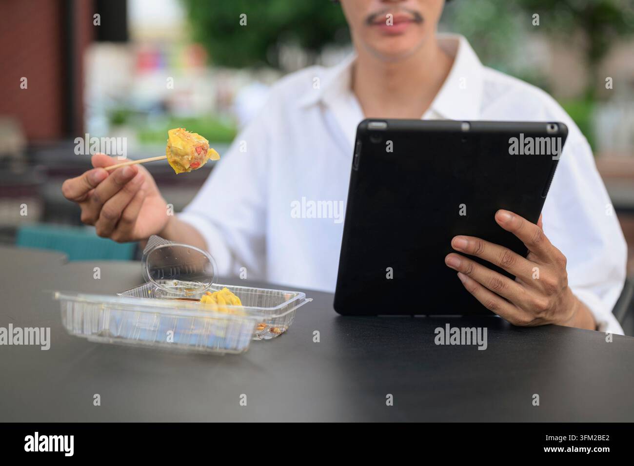 Photographie horizontale en gros plan mettant l'accent sur une perspective mains dans le cadre d'une personne gérant la technologie et le déjeuner dans un lieu extérieur. Le cache de cadre Banque D'Images